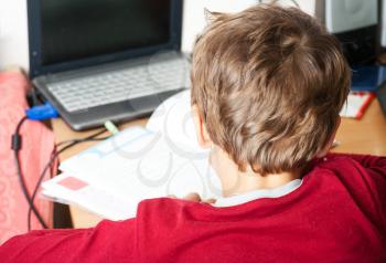 boy writing indoors, back side view