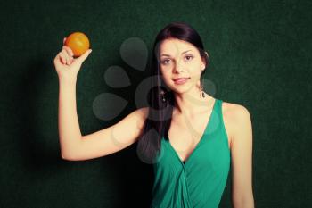 Cute girl show the ripe orange. Female with an orange in her hands