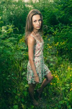 Beautiful Young Woman standing in Meadow of Flowers. Enjoying Nature
