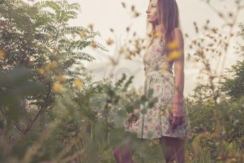 Beautiful Young Woman standing in Meadow of Flowers. Enjoying Nature