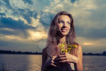 Cute female smiling and looking up. Young woman posing on the sunset panorama of river