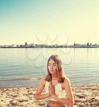 girl meditating near lake on the sandy coast