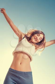 Free and happy women. Blonde teenager female jumping with the blue sky in the background