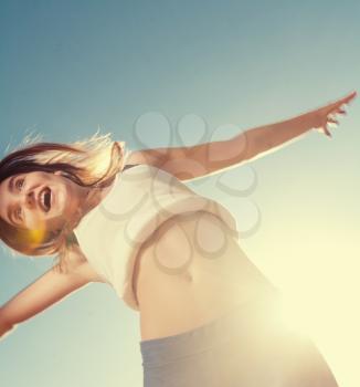 Creative angle view of the Blonde teenager girl jumping happy with the blue sky in the background