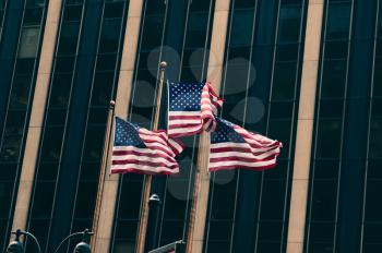 Three US flags against glass wall
