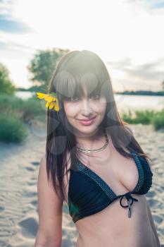 Sensual girl with sunflower in her  long brown healthy hair outdoors.