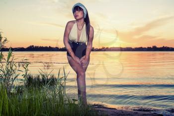 Retro-looking attractive women outdoor portrait. Girl at sunset full body shot. Colorized image