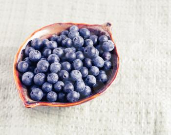 Bowl full of fresh blueberry on rustic tablecloth