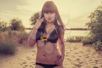 Women on beach with sunflower in her breasts