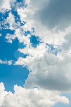 Vertical shot of the blue sky half-hidden by clouds. Clouds and sky background