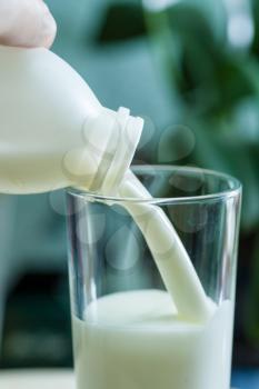 Vertical shot of a milk poured in glass cup over indoors background