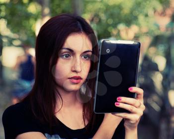Women with tablet PC in her hands outdoors. Female Student looking at screen of tablet-pc