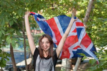 Happy young women with Union Jack in her hands outdoors.