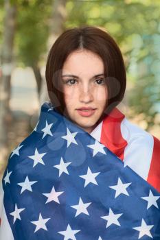 Happy young woman warp in US american flag.