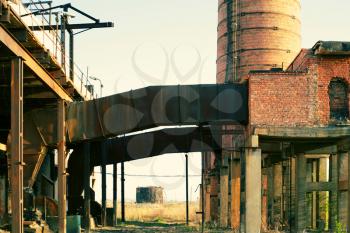 Ruins of a very heavily polluted industrial factory backlit at sunset