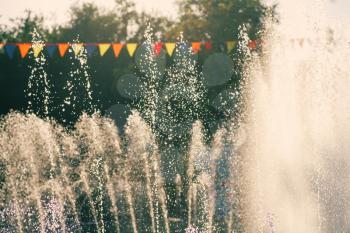 Vintage holidays shot. Jets of a city park fountain and colorful flags