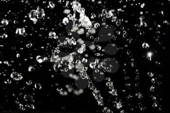 Water levitation. Bright drops flying in the air on black background
