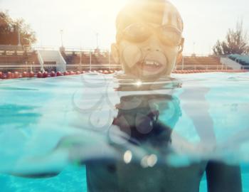 Young boy swimming with half of face under water backlit image
