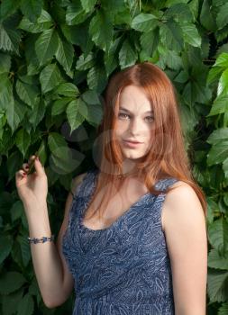 Ginger haired women posing in green leaves outdoor.s