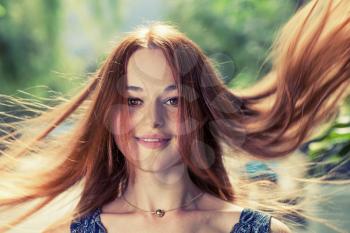 Redhead women with her long hair flying in the air by wind.
