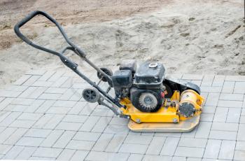 Small yellow compactor standing on new gray  pavement