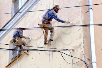 Two unrecognizable painters repair facade