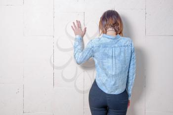 Rear view of a young woman in trendy wear in front of painted wall with space for text