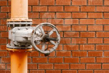 Natural gas distribution system valve in front of orange brick wall with place for text vintage color-look