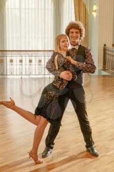 Happy couple dancing latino dance in ballroom toned image