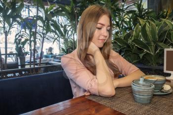 Side view of beautiful lady lond blond hair looking at sugar bowl on table in front of her. Copyspace Image Of sweetheart Having Coffee Drink in melancholy mood