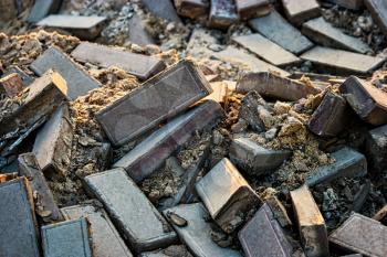 Damaged pavement after earthquake. Many bricks mixed with sand backlit.