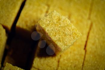 One sugar cube is set over other. Brown sugar cubes above view, lit from the side.
