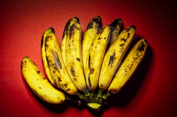 Bunch of overly riped bananas on red background. Fresh organic Banana, Fresh bananas on kitchen table top view, shot with harsh vignette. Group, harvesting.