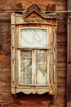 Close up of wooden window in russian country house with half broken decorations.