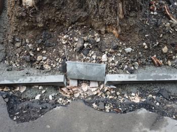 Curb stone installation. Damaged asphalt surface and bare ground around. Copyspace.