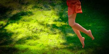 Fun in summertime. Flying girl legs, jump over the fresh grass