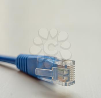 Single blue RJ45 CAT6 shielded network data internet cable connector on gray background with copyspace on top.
