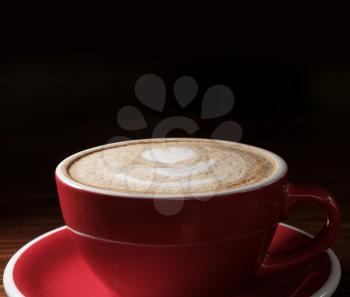 Coffee cup on dark background with copyspace. Latte art o9n top froth, above view.