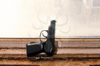 Hand gun placed on used windowsill. Home protection concept.