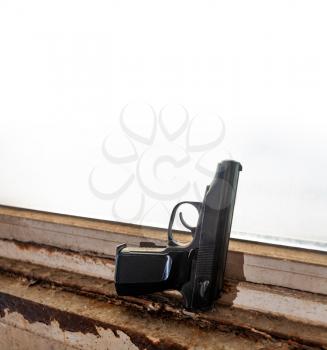 Hand gun placed on used windowsill. Home defence against crime. There is an wide discussion all over the world for civil rights and weapon owning.