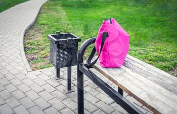 Unique handmade pink fabric handbag by a dressmaker on a bench. Fabric handbag lost on a bench. Cotton fabric handbag.