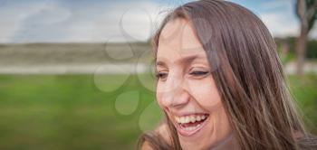 Beautiful woman laughing sincerely outside with her hair on wind.