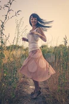 Pretty lady in romantic wear dance in the fields with her black hair flying in an air, blurred motion shot.