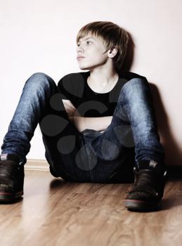 Royalty Free Photo of a Teenager Sitting Against a Wall