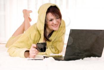 Woman in robe with laptop lying on the floor