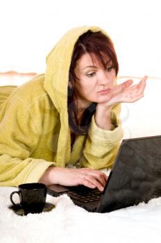 Woman in robe with laptop lying on the floor
