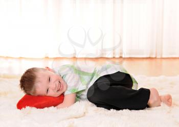 the child is lie on the floor with a red plush heart