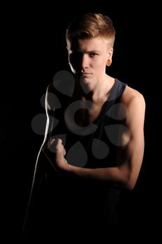 teenager showing muscles on the black background