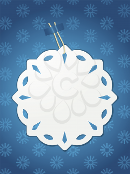 White paper snowflake Christmas label with string taped onto a blue snowflake background