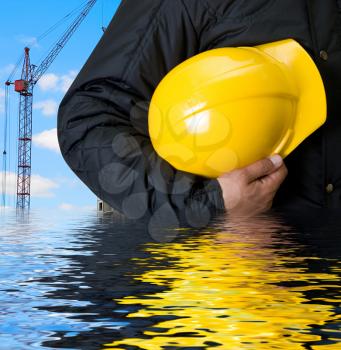 Royalty Free Photo of a Builder Holding a Hardhat in Water